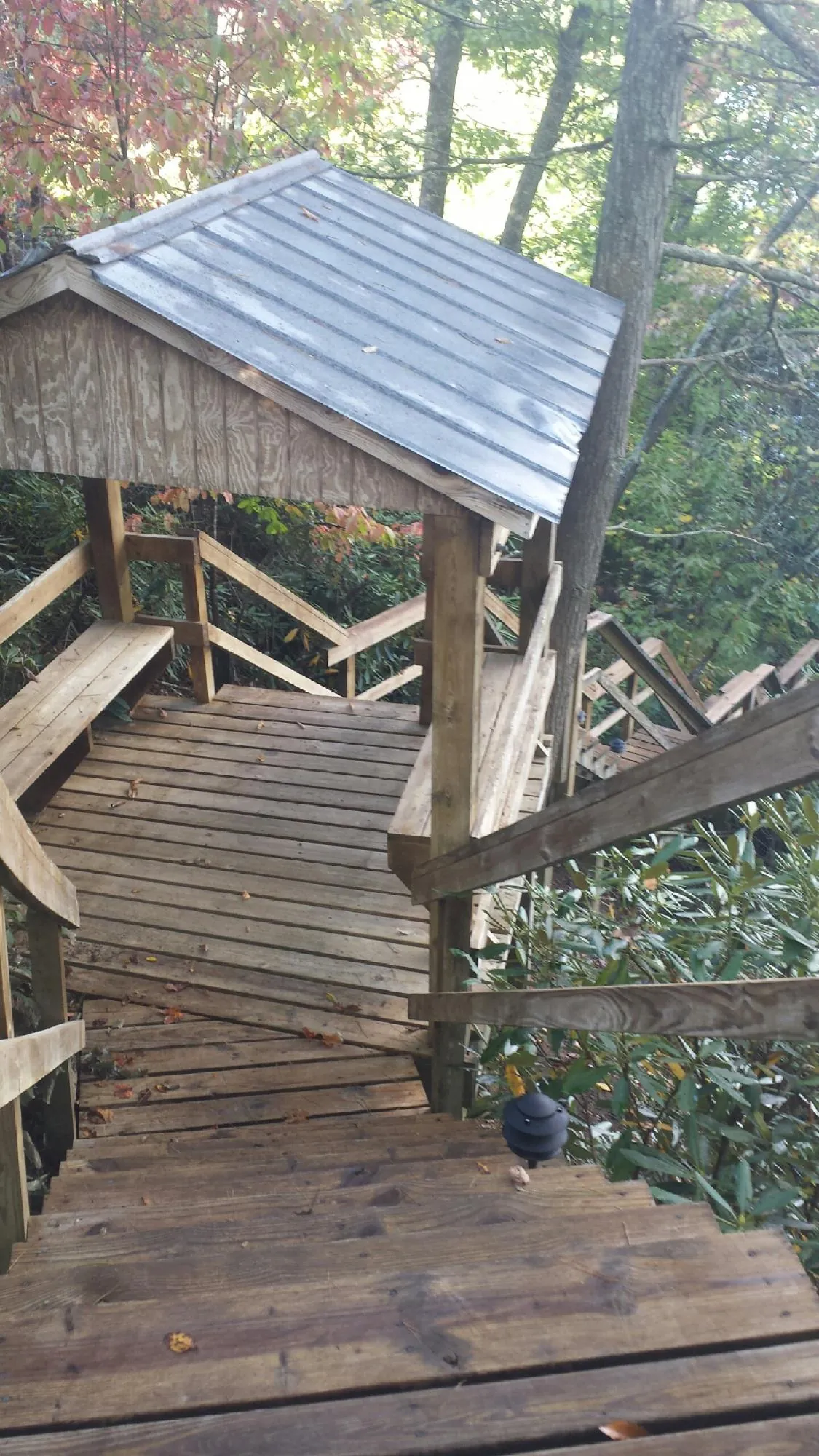 Metal roofed shelter over wooden steps on a wooded walkway — Skylight Repair & Installation work by our crew in Huron